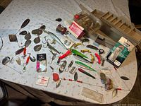 Overall lot on table showing reel box, numerous lures, tackle tray