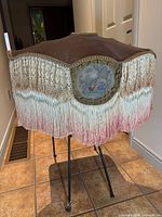 Front view showing scalloped frame, lace trim, ombré fringe and tapestry insert