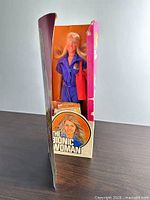 Side view of boxed doll showing interior and accessories