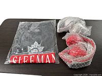 Sealed SLEEMAN T-shirt and two bubble-wrapped Budweiser headphones on table