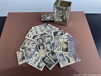 Pile of cigarette cards with tin and lid visible