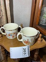 Two Royal Doulton Bunnykins two-handled cups on table