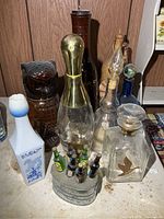 Group of assorted glass, ceramic and wood bottles/decanters on tabletop