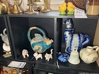 Overall shelf view showing fish teapot, animal figurines, horse decanter, bell, jug, glass heart