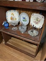 All items grouped on shelf showing plates, glassware, jug, spoons