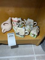 Group shot of five cottage teapots, pink creamer and bud vase