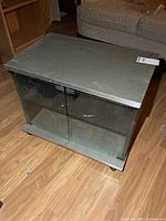 Front view of TV stand showing glass doors and casters