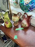 Three porcelain ewer vases on wooden surface