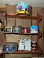 Overall view of wall shelf holding various vintage tins and beer can