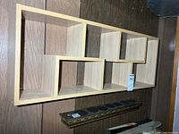 Front view of light wood abstract wall shelf showing five cubbies