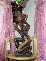 Full view of carved wooden figure on chair