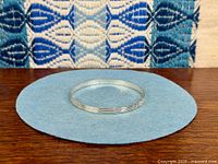 Top view of sterling silver bangle on blue cloth showing circular shape and grooved pattern