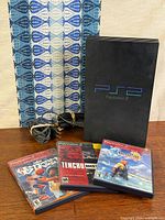 Console standing with cables bundled and three game cases displayed