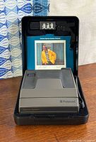 Camera inside open protective case with instruction card and strap visible