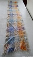 Full view of mohair scarf laid flat showing length and plaid colors