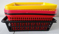 Stack of nested plastic storage baskets showing colors red, yellow and black