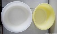 Top view of white and yellow plastic dishpans showing interior and shape