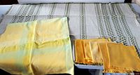 Overview of yellow plaid tablecloth, six yellow napkins and green woven tablecloth