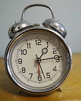 Front view of chrome metal twin bell alarm clock showing dial and hands