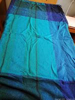 Full view of blue-green plaid wool blanket spread on bed