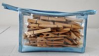 Clear vinyl pouch with blue trim containing numerous wooden clothespins