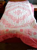 Full view of quilt spread on bed displaying overall pink and white log cabin pattern