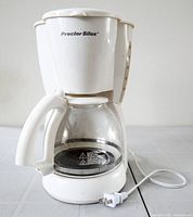 Front view of white Proctor Silex coffee maker with carafe and cord