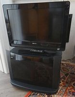 Sony 26" TV placed on Panasonic stand, remote visible on stand top