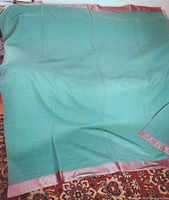 Full view of green wool blanket with satin border