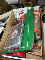 Tray showing multiple Coca-Cola collectibles including straw tin, clipboard, camera, cards and more