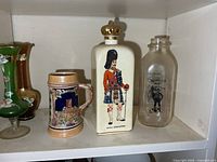 Group view of porcelain decanter, German stein, milk bottle, two glass vases