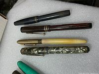 Four pens on foam: black, woodgrain, cream, grey marbled