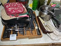 Overview of hot plate, cutlery tray, carving knife blades, saucepan, pot holders
