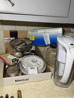 Tray showing assorted kitchen items including strainer, CorningWare lid, timer, egg cups, skewers, pastry blender, Brita filter box and pitcher