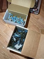 Two open cardboard boxes containing mixed blue, grey and green plastic soldiers