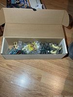 Open cardboard box filled with assorted plastic figures