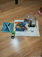 Catalog, boxed airplane, loose race car, bag with two cars