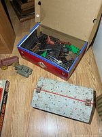Box of assorted brown plastic ranch/fence parts, red horse, metal hut alongside