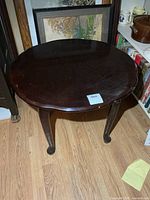 Top view of dark stained oval wood side table showing surface wear and chip