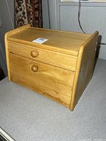 Front view of wooden breadbox showing drop-front door and knob pull