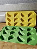 Front view of both green and yellow silicone ice cube trays