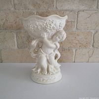 Front view of off-white cherub planter showing full design and base