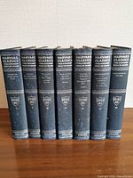 Front view of all seven volumes showing spines with series title, publisher shield and volume numbers
