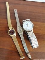All three wristwatches laid flat displaying dials and bracelets