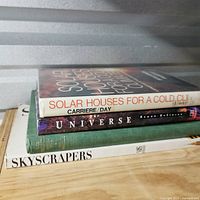 Stack of four hardcover books showing three visible titles on spines