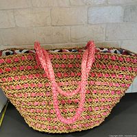 full view of woven raffia tote with pink accents and handles
