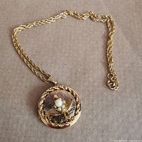 Full view of gold-tone floral locket on chain