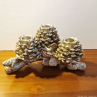 Front view of silver pinecone candleholder showing three candle cups