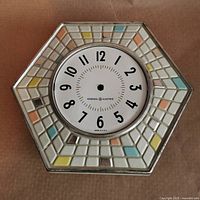 Front view of mosaic hexagonal clock face, showing dial and tile border
