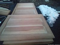 Three unfinished wood cabinet doors stacked outdoors